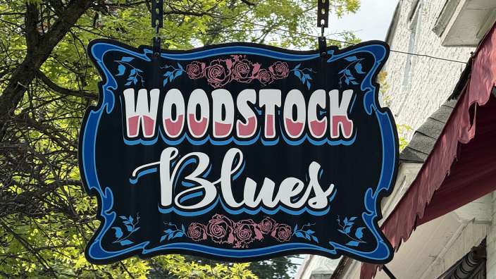 Ein blaues und weißes Schild hängt an einem Gebäude und sagt " woodstock blues "
