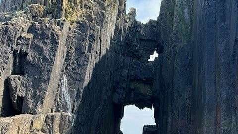 Eine Felsformation mit einem Bogen in der Mitte des Ozeans