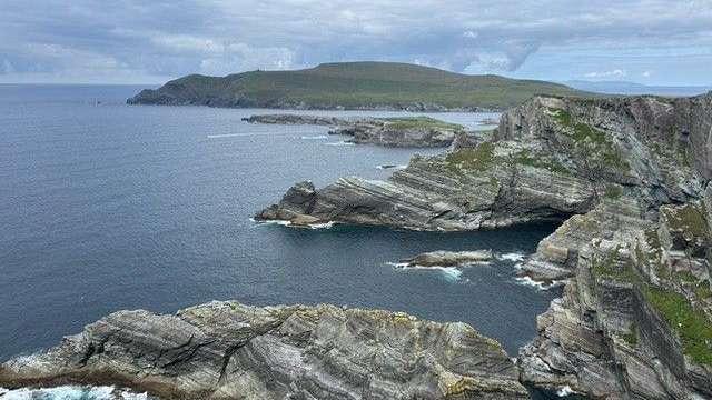 Eine felsige Küste mit einem kleinen Hügel im Hintergrund