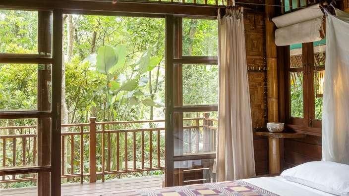 Ein Schlafzimmer mit einem Bett und einem Balkon mit Blick auf den Dschungel