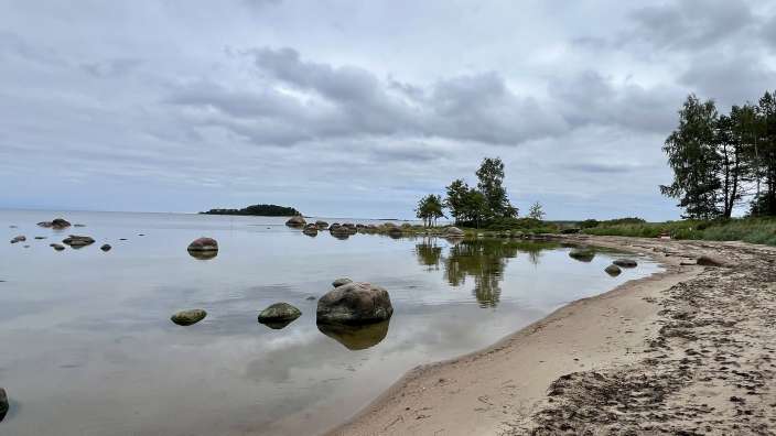 Ein Strand mit einem großen Felsen im Wasser
