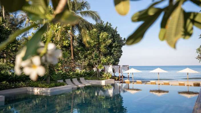 Ein Infinity-Pool mit Liegestühlen und Sonnenschirmen am Strand