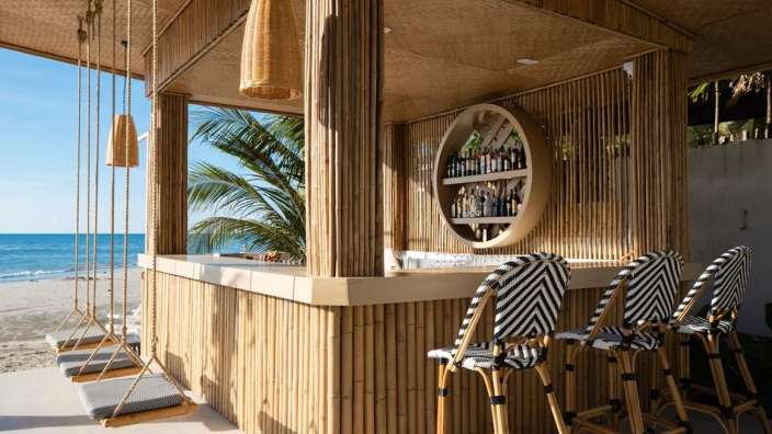 Eine Bar mit Schaukelstühlen und Flaschen an der Wand