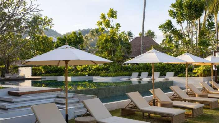 Liegestühle und Sonnenschirme stehen neben einem Pool