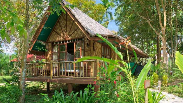 Ein kleines Holzhaus mit Strohdach und einem Balkon