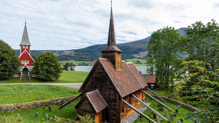 Eine kleine hölzerne Kirche mit einem roten Turm neben einem See