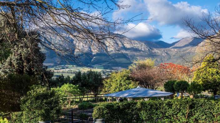 Franschhoek I Mont Rochelle Ein Garten mit einem Zelt und Bäumen und Bergen im Hintergrund