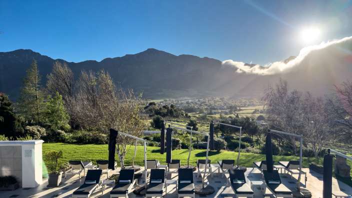 Franschhoek I Mont Rochelle Ein Swimmingpool mit Liegestühlen und Sonnenschirmen und einem Berg im Hintergrund