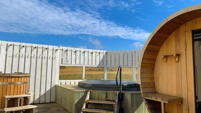 Ein Holzfass neben einem Whirlpool und einer Sauna