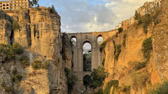 Puerto Nueve in Ronda bei Sonnenuntergang  Eine Brücke, die über einen Wasserfall führt
