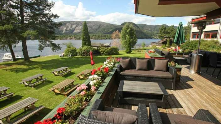 Eine Terrasse mit Möbeln und Picknicktischen mit Blick auf einen See