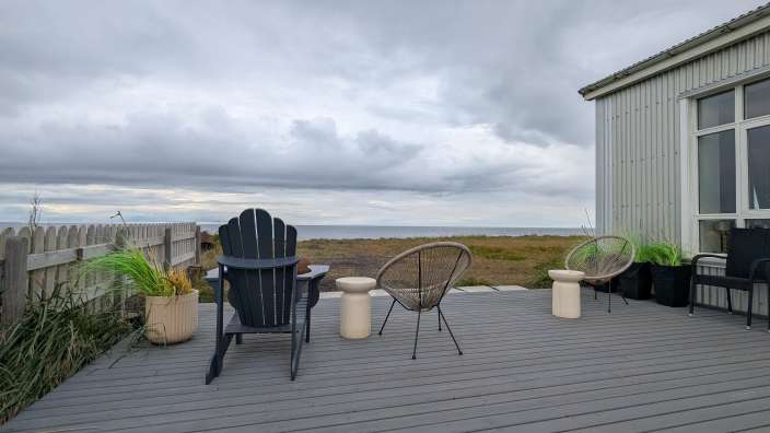 Ein Deck mit Stühlen und einem Tisch mit Blick auf das Meer