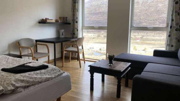 Ein Schlafzimmer mit einem Bett, einem Stuhl, einem Tisch und einem Fenster