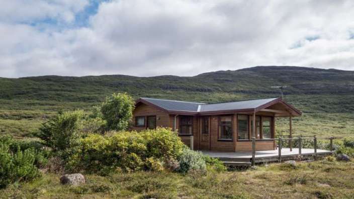 Ein kleines Holzhaus mit einer Veranda in der Mitte eines Feldes .