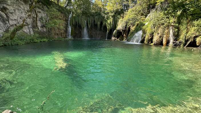 Ein Wasserfall stürzt in einen Pool aus grünem Wasser