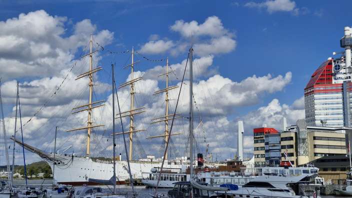 Ein großes weißes Segelschiff liegt in einem Hafen