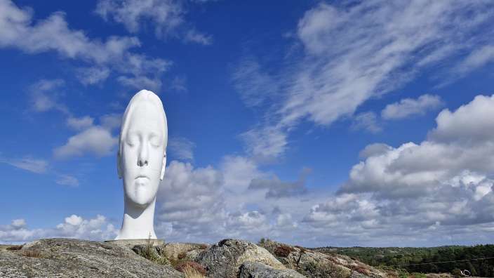 Eine Statue einer Frau mit geschlossenen Augen sitzt auf einem Felsen