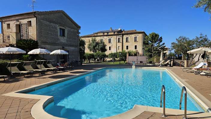 Landgut bei Rossano Ein großer Pool mit Liegestühlen und Sonnenschirmen davor