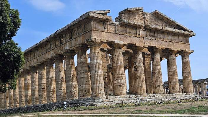 Paestum im Cilento Ein altes Gebäude mit vielen Säulen und einem blauen Himmel dahinter