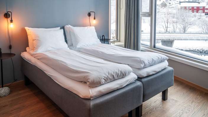 Ein stilvolles Schlafzimmer mit zwei Betten und Blick auf eine verschneite Landschaft.