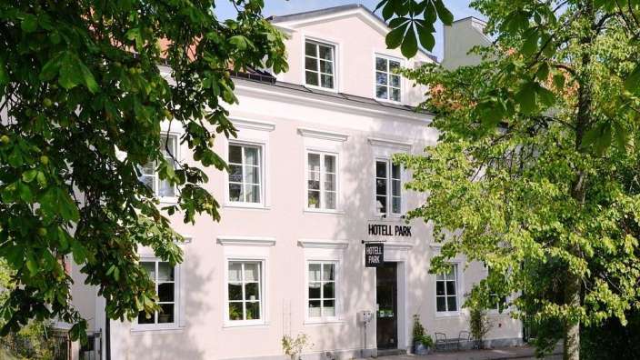 Ein helles Gebäude, wahrscheinlich ein Hotel, wird von üppigen grünen Bäumen umrahmt.