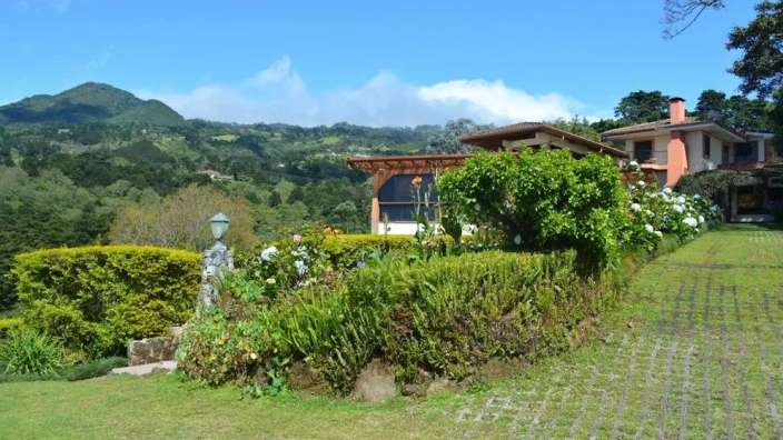 Ein malerisches Haus mit einem Garten und einer schönen Landschaft im Hintergrund.
