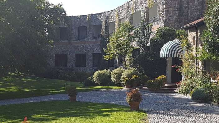 Ein Gebäude aus Stein mit einem begrünten Innenhof und einer gepflasterten Auffahrt.