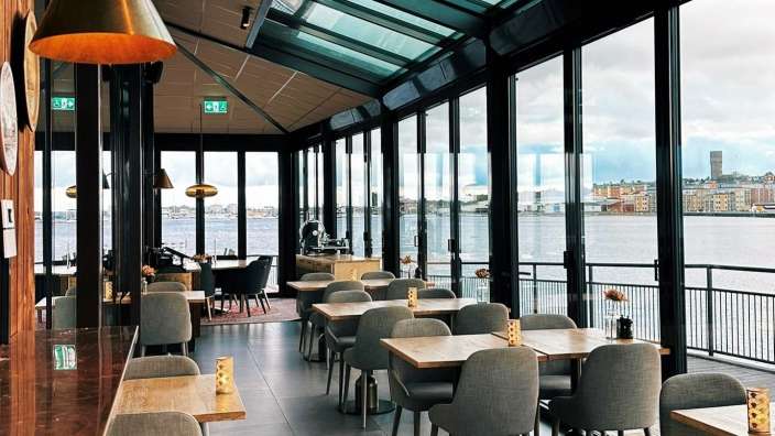 Ein Restaurant mit Blick auf das Wasser und einer Glasdecke.
