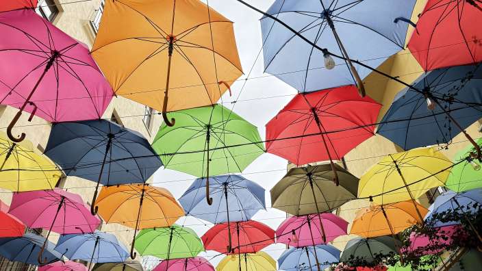 Viele bunte Regenschirme hängen als Dekoration von einer Decke.