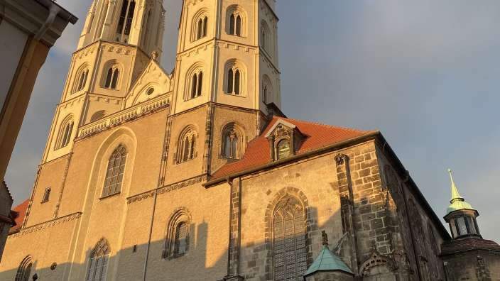 Die Liebfrauenkirche in Legnica besitzt zwei markante, im Sonnenlicht strahlende Kirchtürme und eine historische Steinfassade.