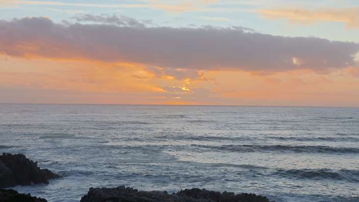 Sonnenuntergang über dem Ozean an einer felsigen Küste in Gansbaai.
