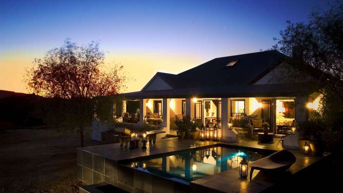 Ein Haus mit einem Pool und einer Veranda bei Sonnenuntergang
