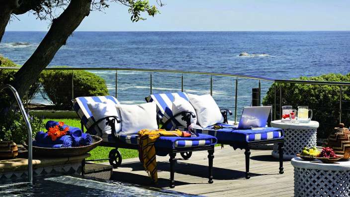 Liegestühle neben einem Pool mit Blick auf das Meer