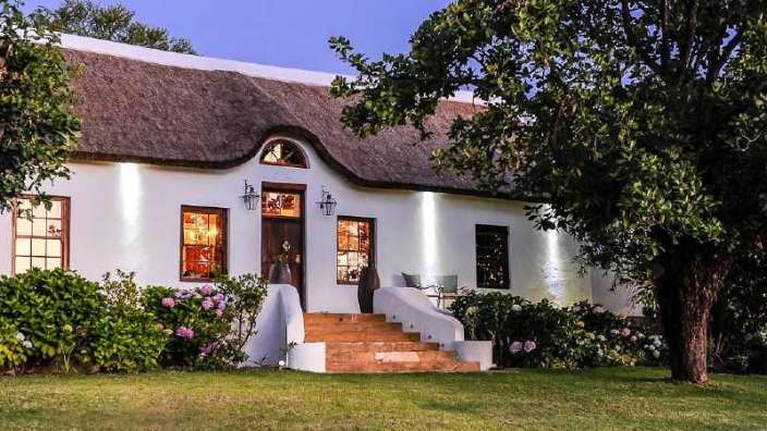 Ein weißes Haus mit strohdach und einer Treppe .