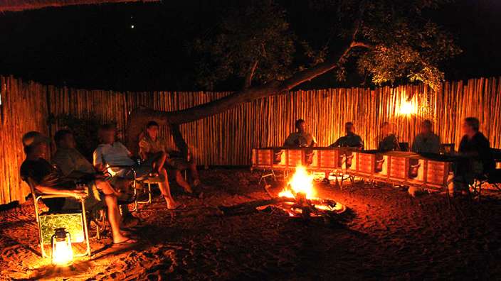 Eine Gruppe von Menschen sitzt um ein Lagerfeuer