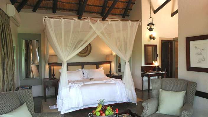 Ein Schlafzimmer mit einem Himmelbett und einem Stuhl