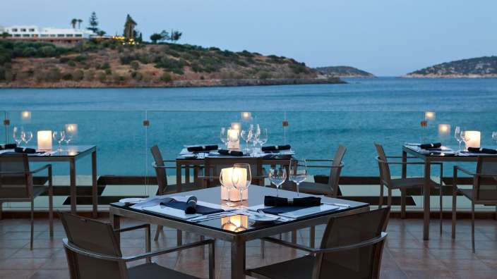 Tische und Stühle auf einem Balkon mit Blick auf das Meer