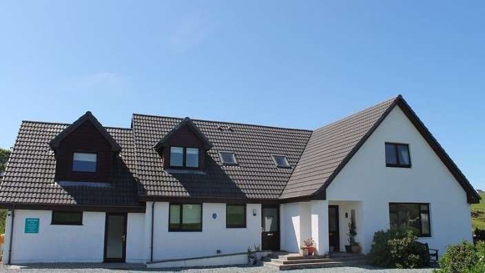 Ein weißes Haus mit einem braunen Dach und vielen Fenstern