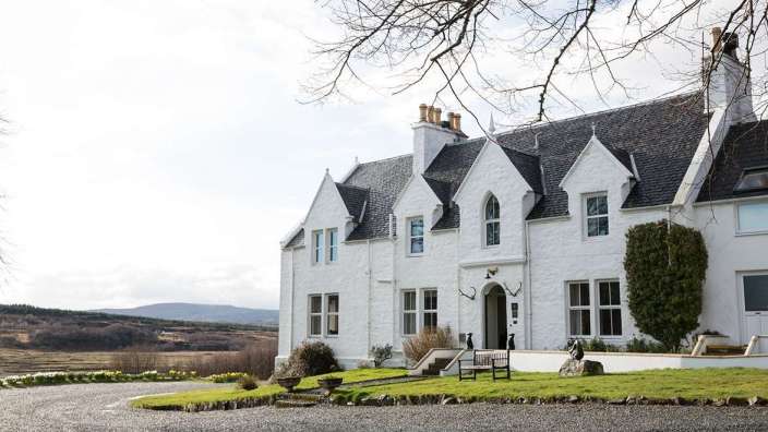 Ein großes weißes Haus mit einem schwarzen Dach und vielen Fenstern
