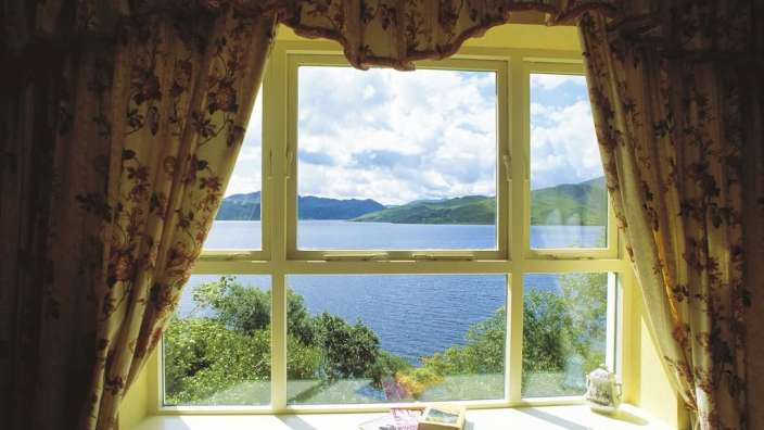 Ein Fenster mit Blick auf einen See und die Berge