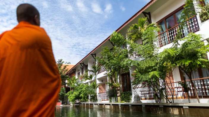 Ein Mann in einem orangefarbenen Kleid steht vor einem Hotel