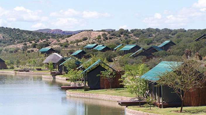 Eine Reihe von Zelten an einem See mit Bergen im Hintergrund