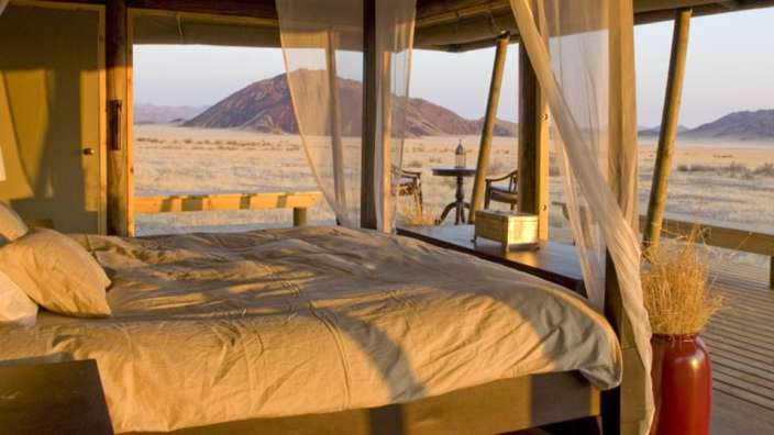 Ein Schlafzimmer mit Himmelbett und Blick auf die Wüste