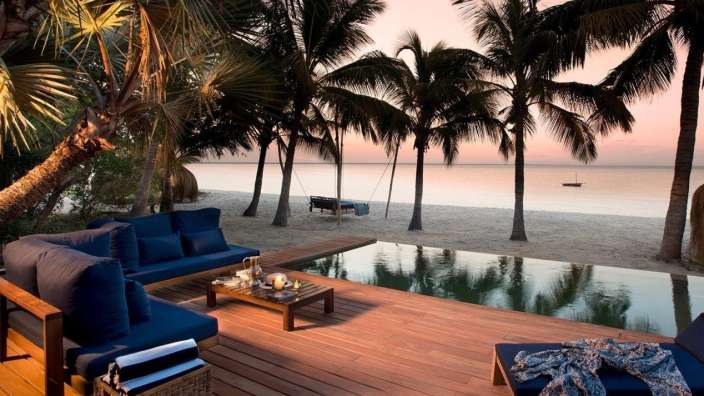 Ein Deck mit einer Couch und einem Tisch neben einem Pool