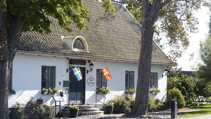 Ein weißes Haus mit einem grünen Dach und einem Schild mit der Aufschrift " gästehaus "