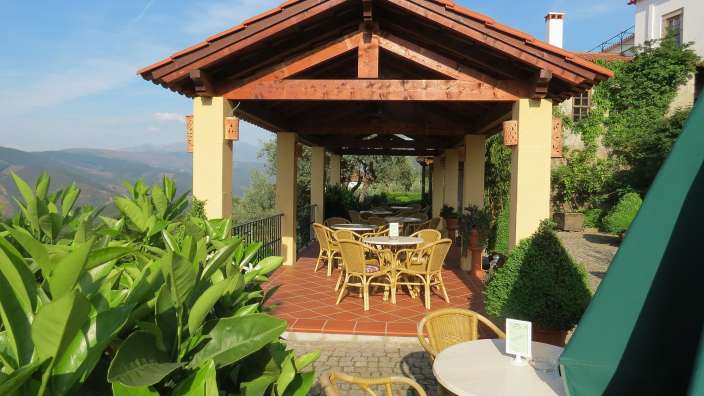 Eine Terrasse mit Tisch und Stühlen unter einem Holzdach