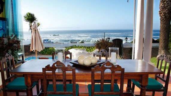 Ein Esszimmer mit einem Tisch und Stühlen mit Blick auf das Meer .
