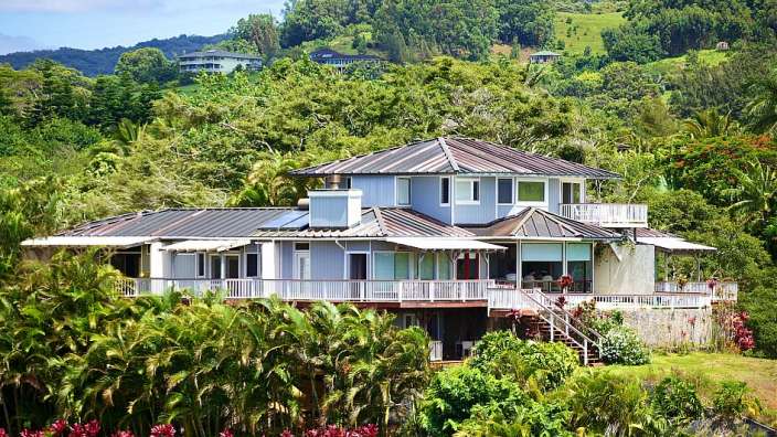 Ein großes blaues Haus steht auf einem Hügel im Dschungel
