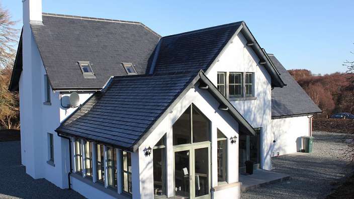 Ein weißes Haus mit schwarzem Dach und vielen Fenstern