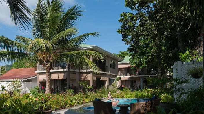 Menschen schwimmen in einem Pool vor einem Haus